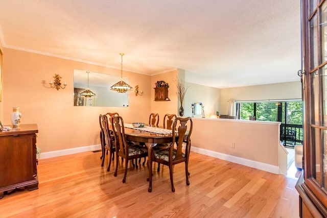 dining space with light wood-type flooring, baseboards, and ornamental molding