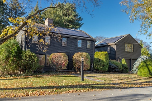 view of front facade with a front lawn, a garage, and solar panels