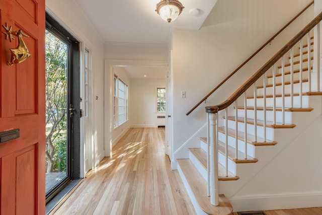 entryway featuring radiator, light wood-type flooring, and ornamental molding