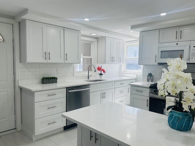 kitchen featuring a sink, light countertops, plenty of natural light, and stainless steel appliances