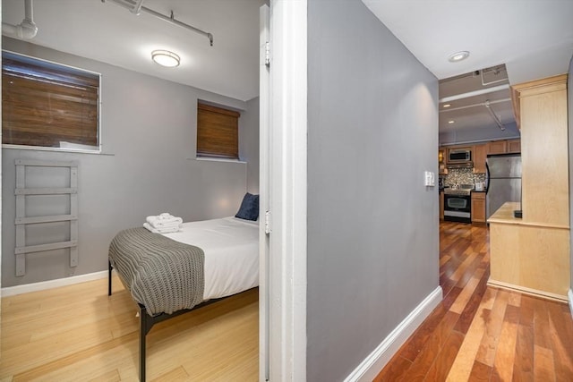 bedroom with freestanding refrigerator, light wood finished floors, baseboards, and recessed lighting