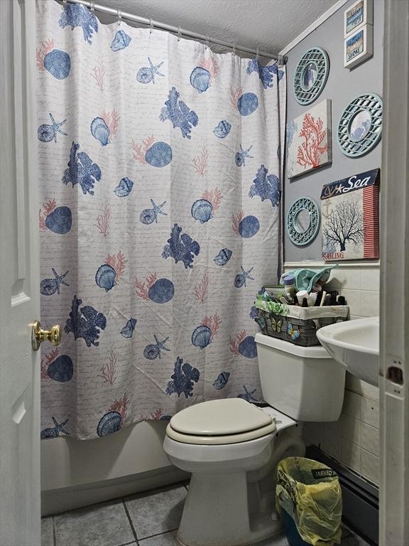 bathroom featuring tile patterned flooring, toilet, a shower with shower curtain, and a textured ceiling