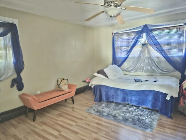 bedroom featuring wood finished floors, baseboards, and ceiling fan