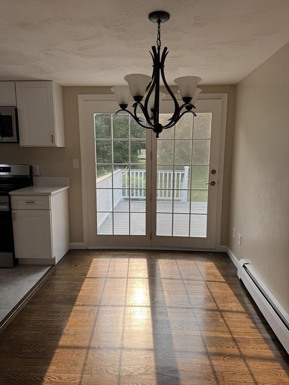 464 Church St, Raynham, MA 02767 - unfurnished dining area with a baseboard heating unit, baseboards, a chandelier, and wood finished floors