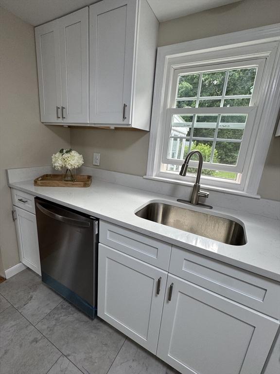 464 Church St, Raynham, MA 02767 - kitchen with dishwasher, a sink, light countertops, white cabinetry, and light tile patterned flooring