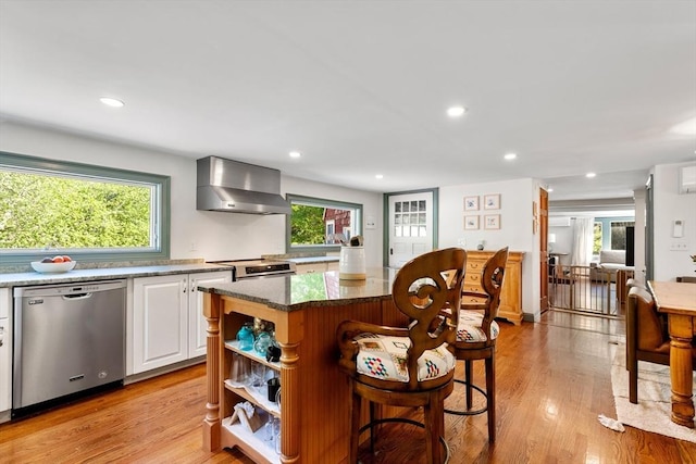 113 Bray St, Gloucester, MA 01930 - kitchen featuring stainless steel dishwasher, wall chimney range hood, a breakfast bar area, white cabinetry, and light wood-type flooring