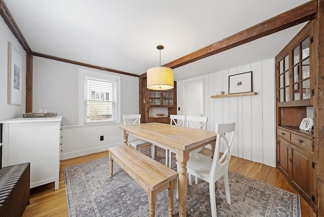 dining space featuring crown molding, baseboards, and light wood finished floors