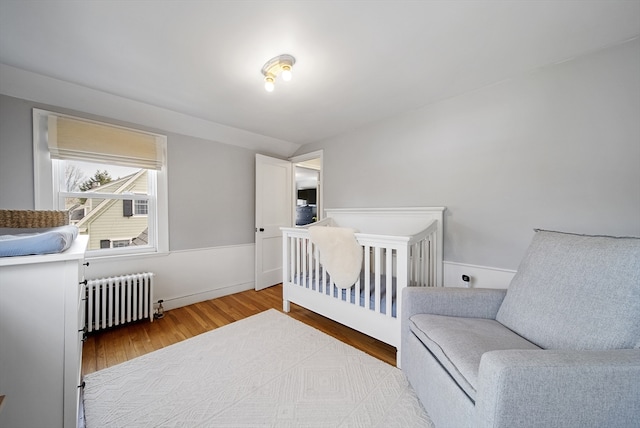 bedroom with wood finished floors and radiator heating unit