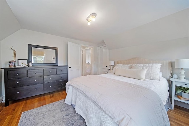 bedroom with lofted ceiling and wood finished floors