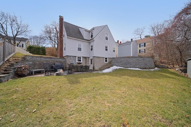 rear view of house featuring a fire pit, a yard, fence, and a chimney