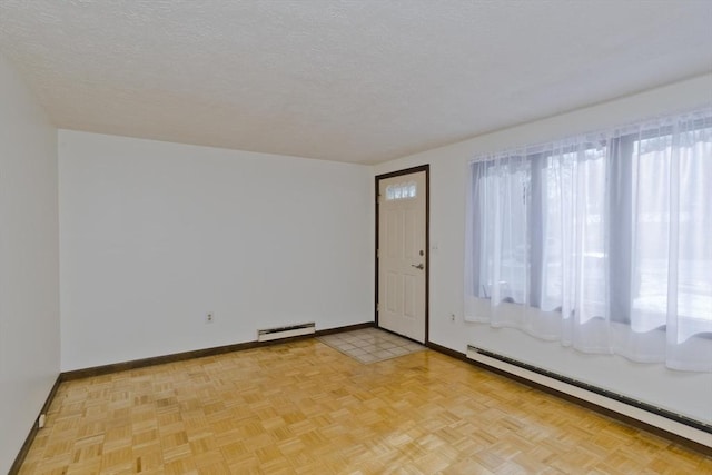 spare room with a baseboard radiator, light parquet flooring, and a textured ceiling