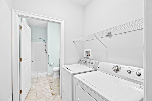 washroom with laundry area, washer and dryer, and light tile patterned flooring