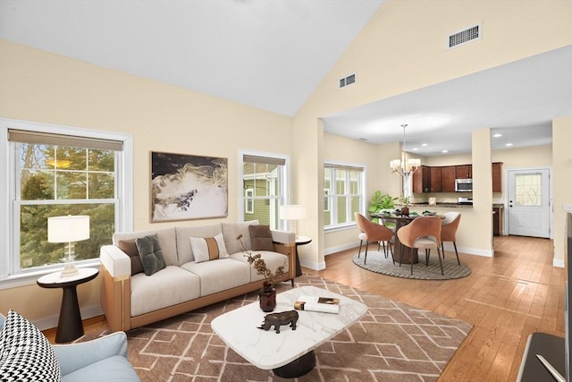 living area featuring an inviting chandelier, baseboards, visible vents, and hardwood / wood-style flooring