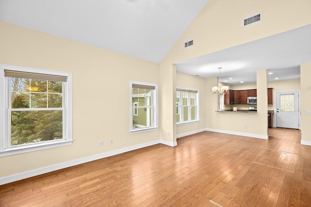 unfurnished living room with light wood-type flooring, baseboards, visible vents, and a notable chandelier