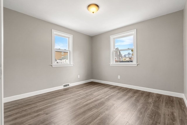 unfurnished room with a wealth of natural light and dark hardwood / wood-style floors