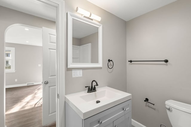 bathroom featuring wood-type flooring, toilet, and vanity