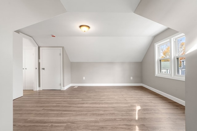 bonus room with light wood-type flooring and vaulted ceiling