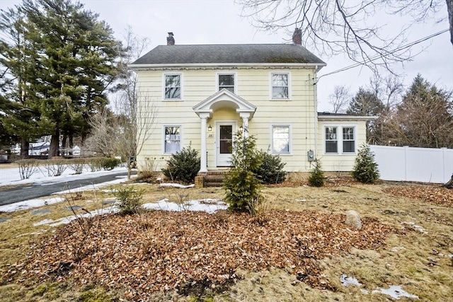 colonial house featuring a chimney and fence