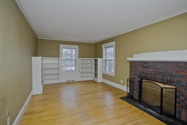 unfurnished living room with baseboards, a brick fireplace, wood finished floors, and crown molding