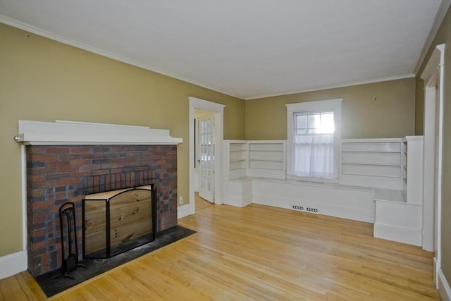 unfurnished living room with a brick fireplace, crown molding, baseboards, and wood finished floors