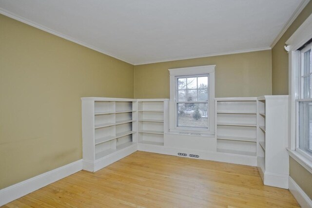 spare room featuring ornamental molding, baseboards, and wood finished floors