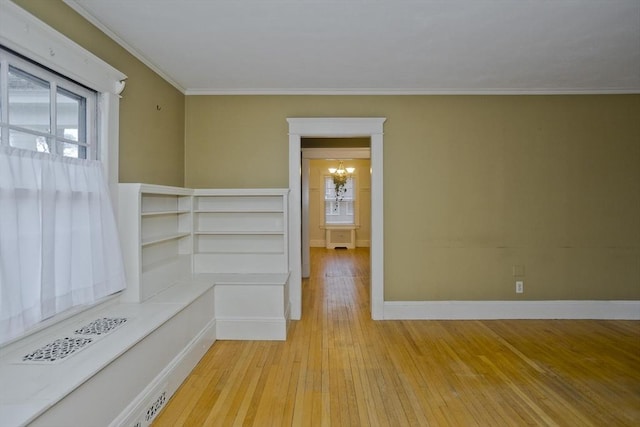 unfurnished room with light wood finished floors, a chandelier, a wealth of natural light, and ornamental molding