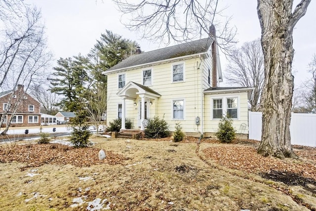 colonial house with a chimney and fence