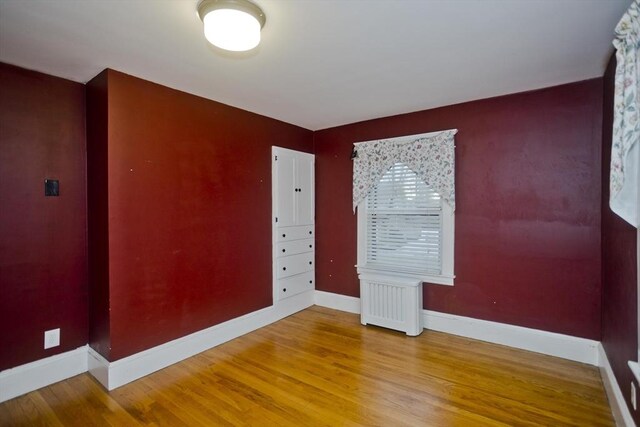 spare room with baseboards and wood finished floors