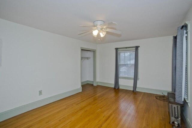 interior space with ceiling fan, radiator heating unit, light wood-type flooring, and baseboards