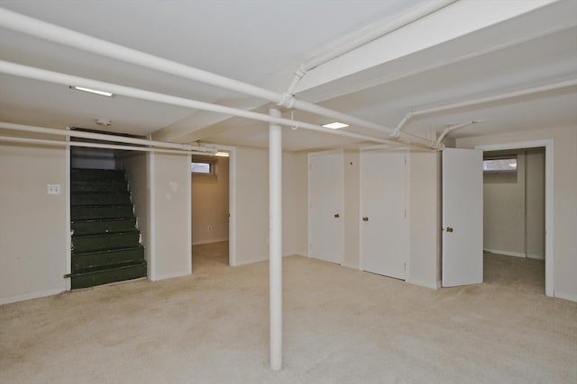 finished below grade area featuring light colored carpet and stairway