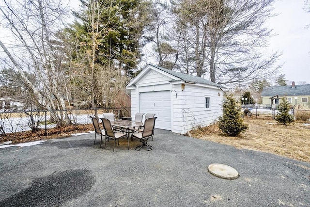 view of patio / terrace featuring a garage, an outbuilding, outdoor dining area, and fence