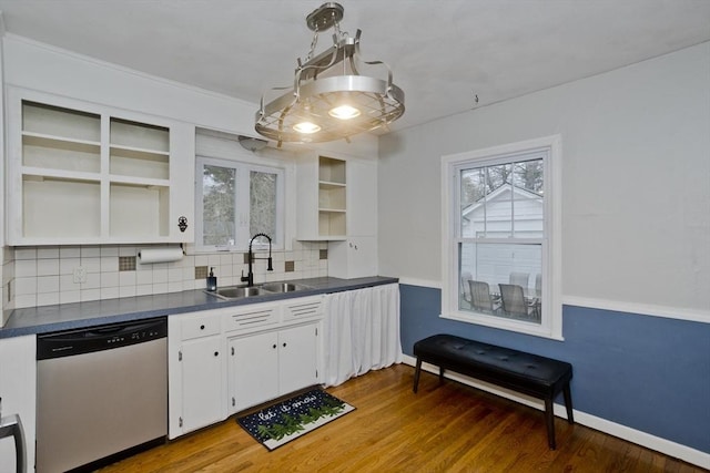 kitchen featuring dark countertops, backsplash, stainless steel dishwasher, open shelves, and a sink