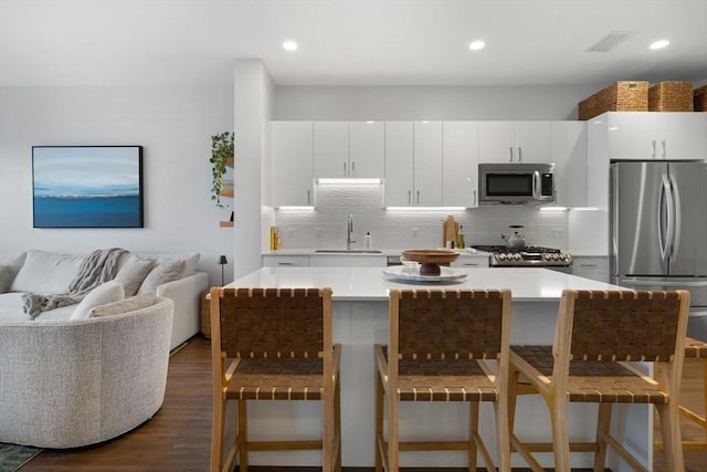 kitchen with a kitchen bar, appliances with stainless steel finishes, backsplash, white cabinets, and sink