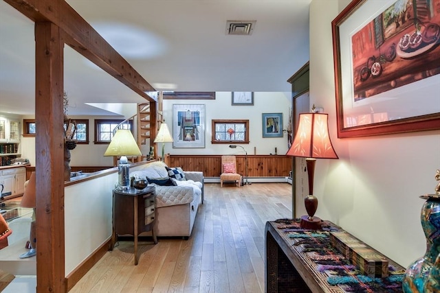 living area with beamed ceiling, light hardwood / wood-style floors, and baseboard heating