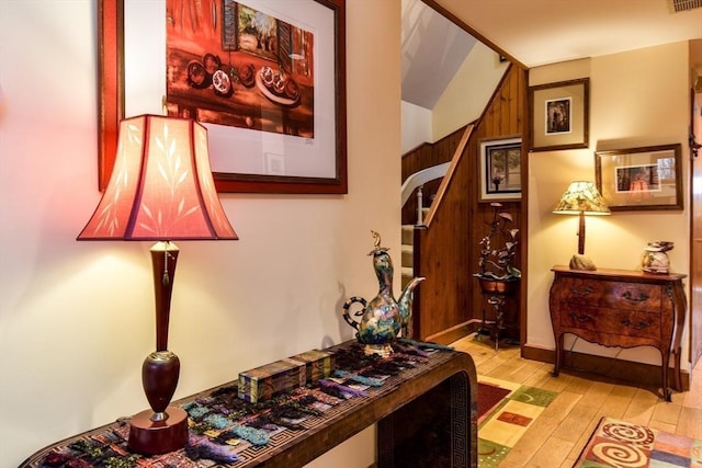 corridor featuring light hardwood / wood-style flooring and wooden walls