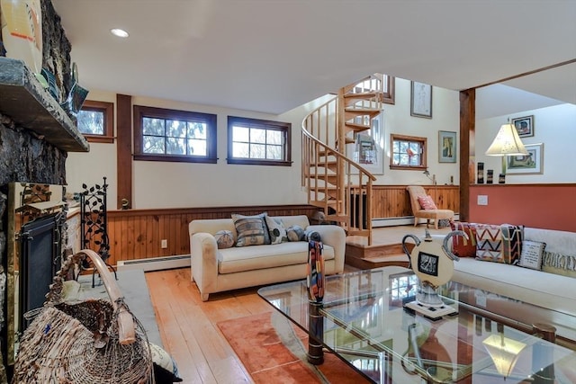 living room featuring baseboard heating, light hardwood / wood-style floors, and wood walls