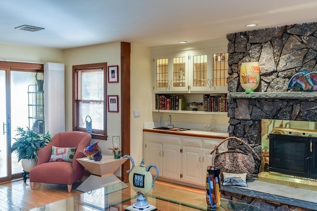 living area with sink, a fireplace, and light wood-type flooring