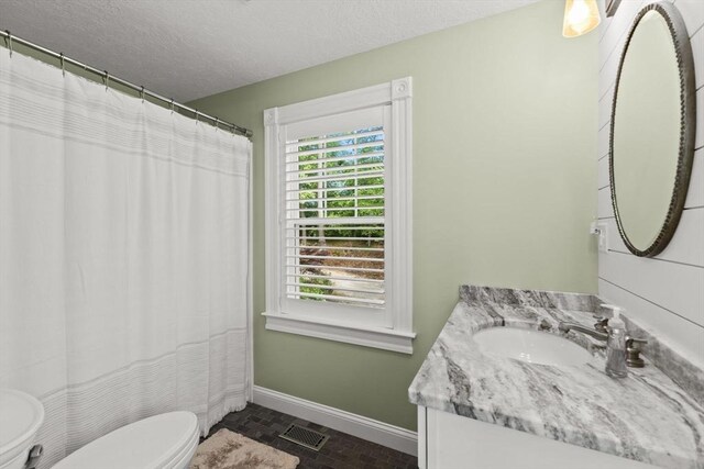 192 Furnace Ln, Pembroke, MA 02359 - full bathroom with baseboards, toilet, vanity, brick patterned floors, and a textured ceiling