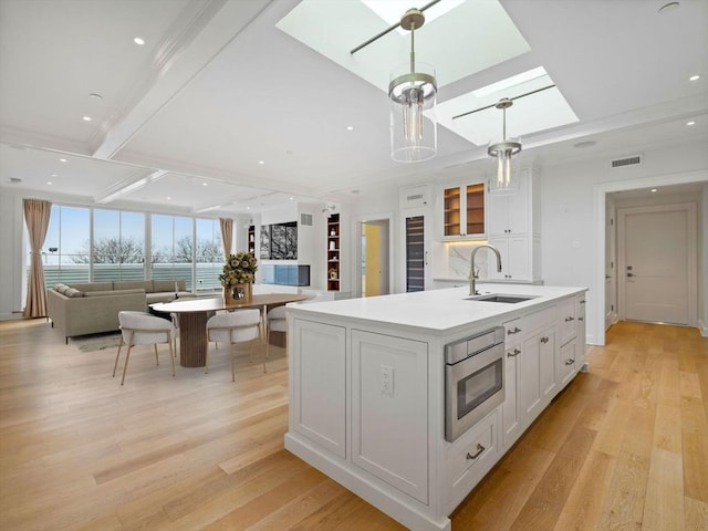 kitchen featuring a skylight, a sink, visible vents, and light wood-style floors