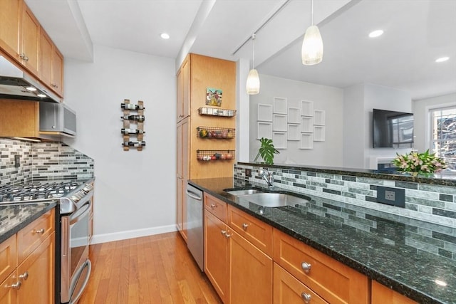 kitchen with stainless steel appliances, tasteful backsplash, dark stone countertops, hanging light fixtures, and sink