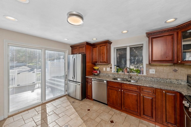 kitchen with light stone counters, sink, decorative backsplash, and stainless steel appliances