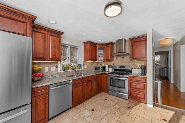 kitchen featuring backsplash, light stone countertops, wall chimney exhaust hood, and stainless steel appliances