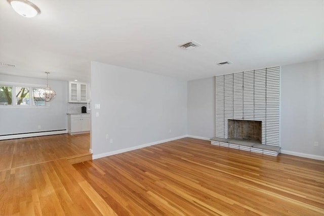 150 Gore Rd, Revere, MA 02151 - unfurnished living room with light wood finished floors, a tile fireplace, a baseboard heating unit, and a chandelier