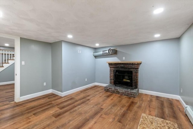 150 Gore Rd, Revere, MA 02151 - unfurnished living room featuring wood finished floors, stairs, a baseboard heating unit, a brick fireplace, and recessed lighting