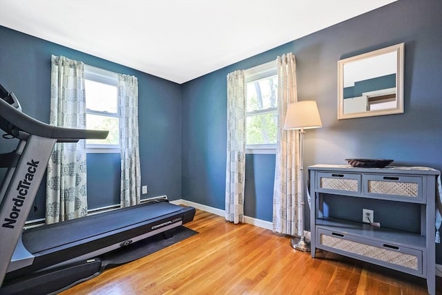 exercise area with plenty of natural light, wood finished floors, and baseboards