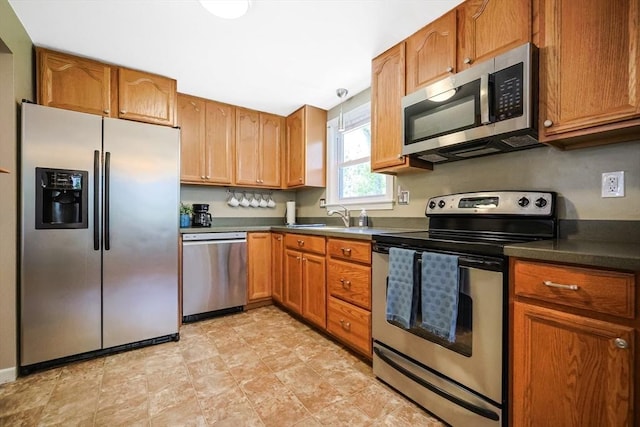 kitchen featuring appliances with stainless steel finishes, brown cabinets, and dark countertops