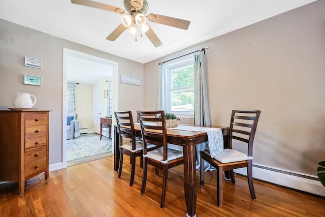 dining space with light wood finished floors, a ceiling fan, a baseboard radiator, and baseboards