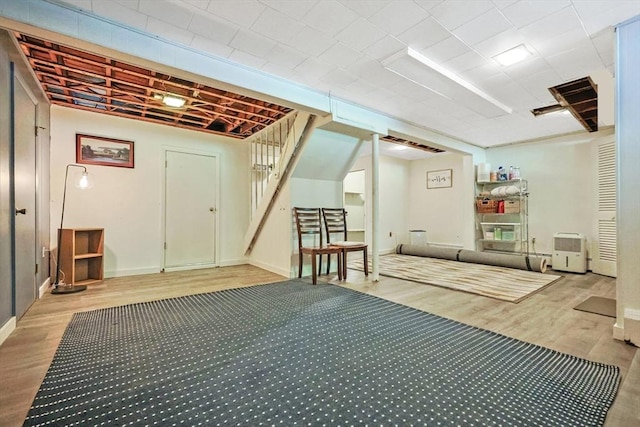 finished basement featuring wood finished floors, baseboards, and stairway