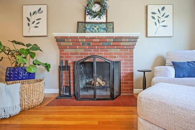 detailed view of a brick fireplace, wood finished floors, and baseboards