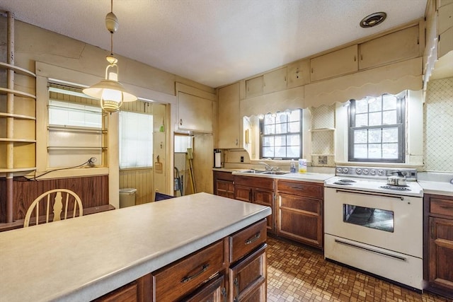 kitchen with pendant lighting, wooden walls, white electric range oven, and sink